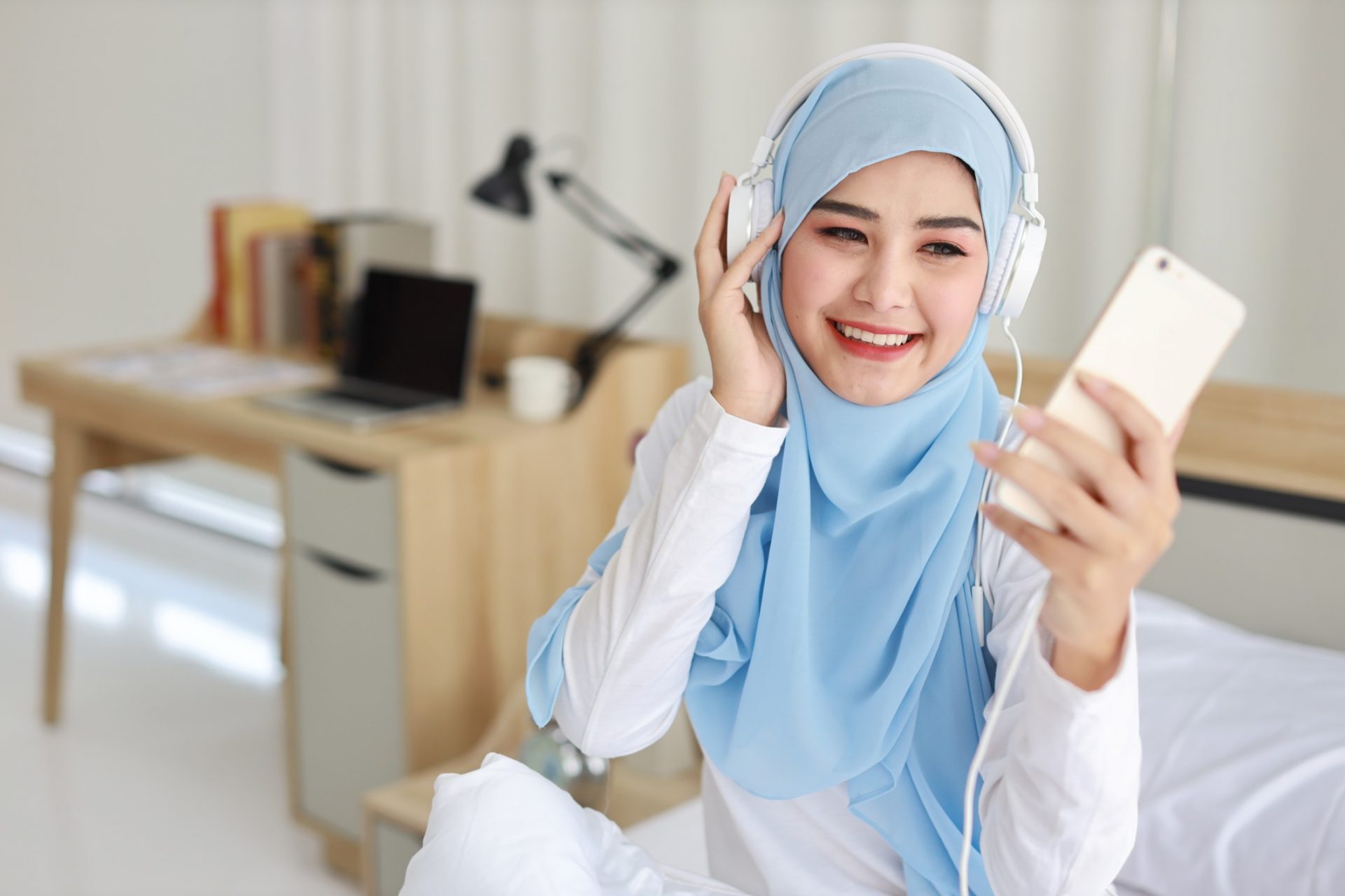 portrait-of-beautiful-asian-muslim-female-in-sleepwear-watching-online-story-on-mobile-phone